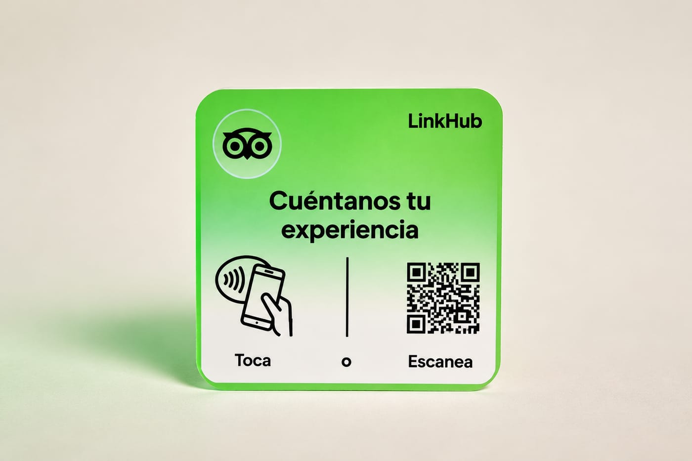 Placa mini de LinkHub con el logotipo de búho de Tripadvisor, el texto «Cuéntanos tu experiencia», el ícono para tocar con el celular y un código QR, sobre un fondo claro