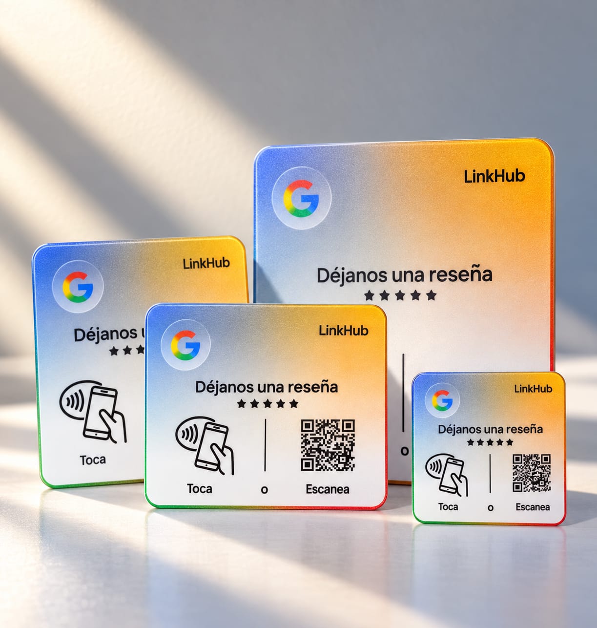 Cuatro placas de LinkHub para reseñas de Google en distintos tamaños, todas con el texto «Déjanos una reseña», el ícono para tocar con el celular y un código QR, bajo luz de ventana