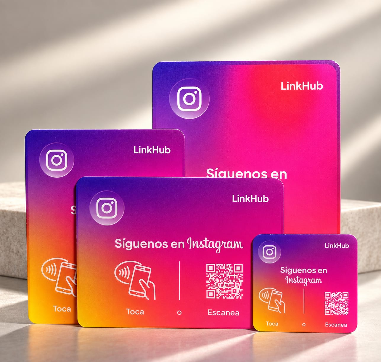 Las cuatro medidas de placa LinkHub, de la mini cuadrada a la de mesa, en un diseño rosado y morado con «Toca» o «Escanea» y un código QR