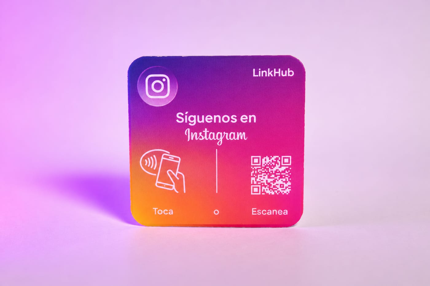 Placa mini cuadrada de LinkHub con degradado morado, rosado y naranja, el logo de Instagram, el texto «Síguenos en Instagram», el dibujo de un celular que toca la placa y un código QR