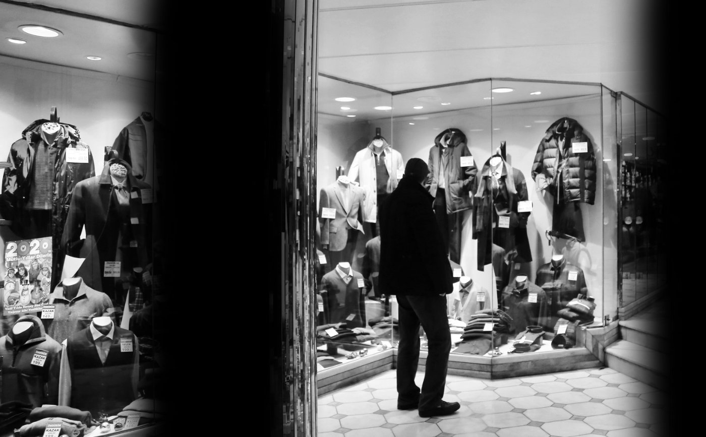 Persona observa la vitrina de una tienda de ropa desde la calle sin entrar al local