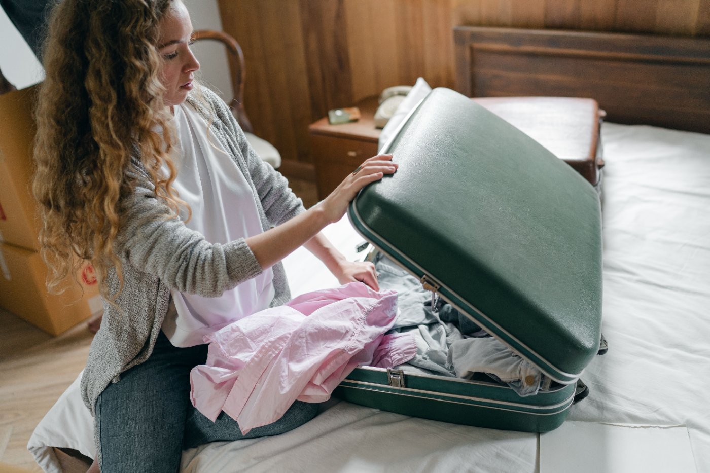 Alt: Viajero recién llegado a la habitación de un alojamiento con su maleta y el celular en la mano