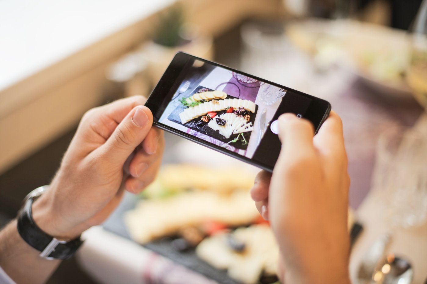 Persona fotografiando con el celular un plato en un restaurante para publicarlo