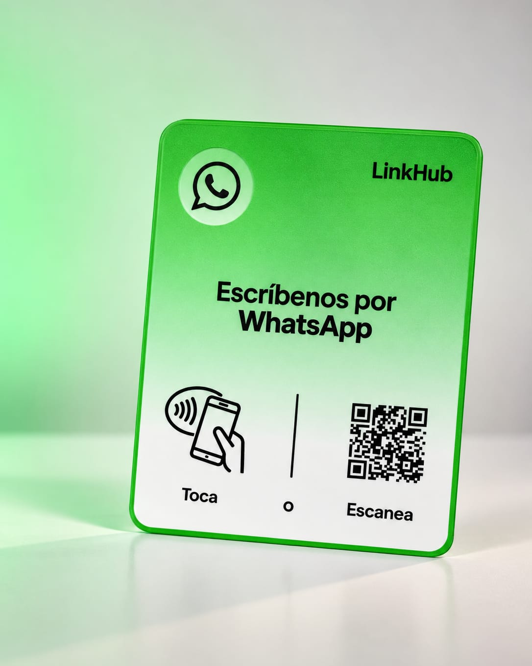 Placa vertical verde de LinkHub con el logo de WhatsApp y «Escríbenos por WhatsApp», levemente girada, con el ícono para tocar y un código QR