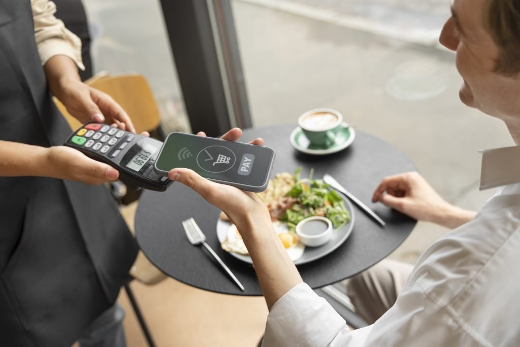 Cliente en un restaurante de Medellín usando su celular en la mesa para dejar una reseña