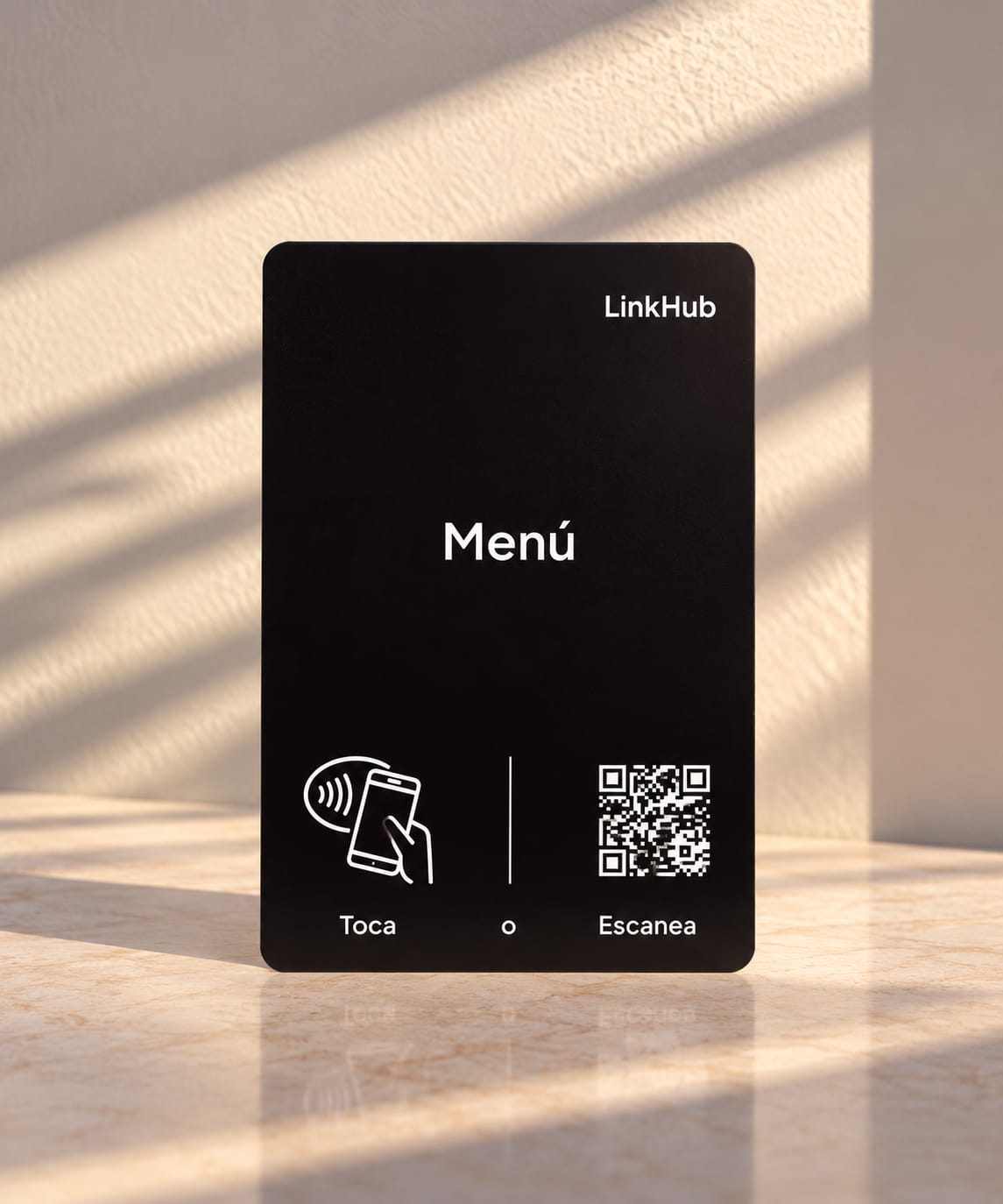 Placa negra de LinkHub con la palabra «Menú», el ícono para tocar con el celular y un código QR, sobre una mesa de mármol con luz de mañana
