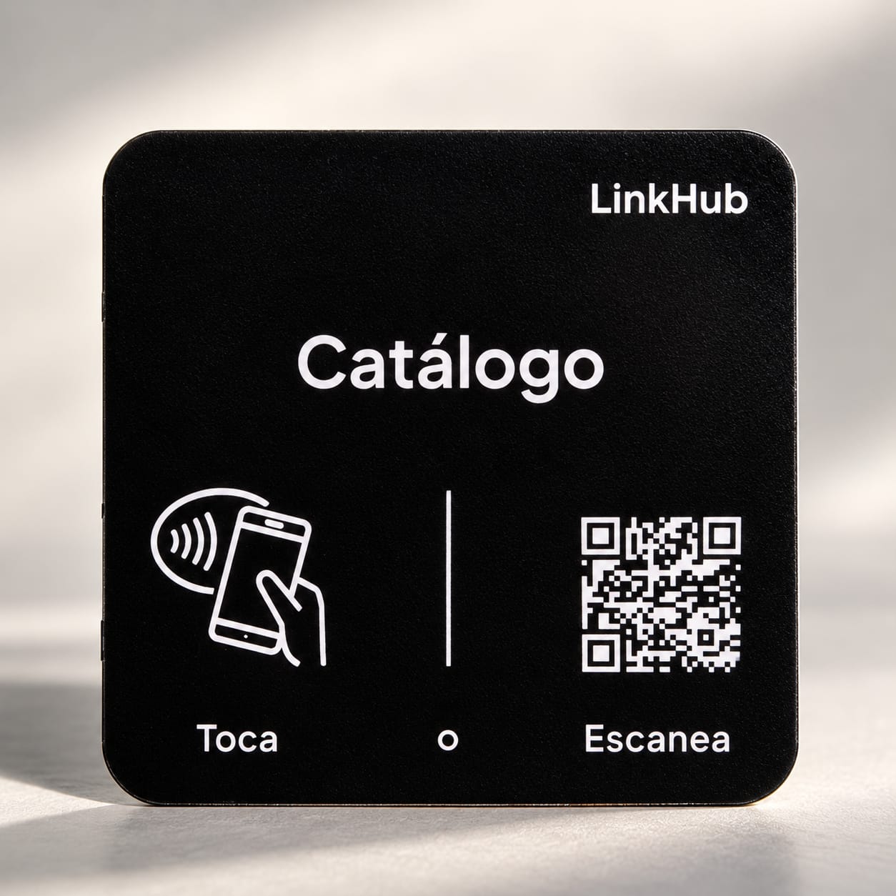 Placa mini negra de LinkHub con «Catálogo» en letras blancas, el dibujo de una mano con un celular sobre «Toca» y un código QR sobre «Escanea»