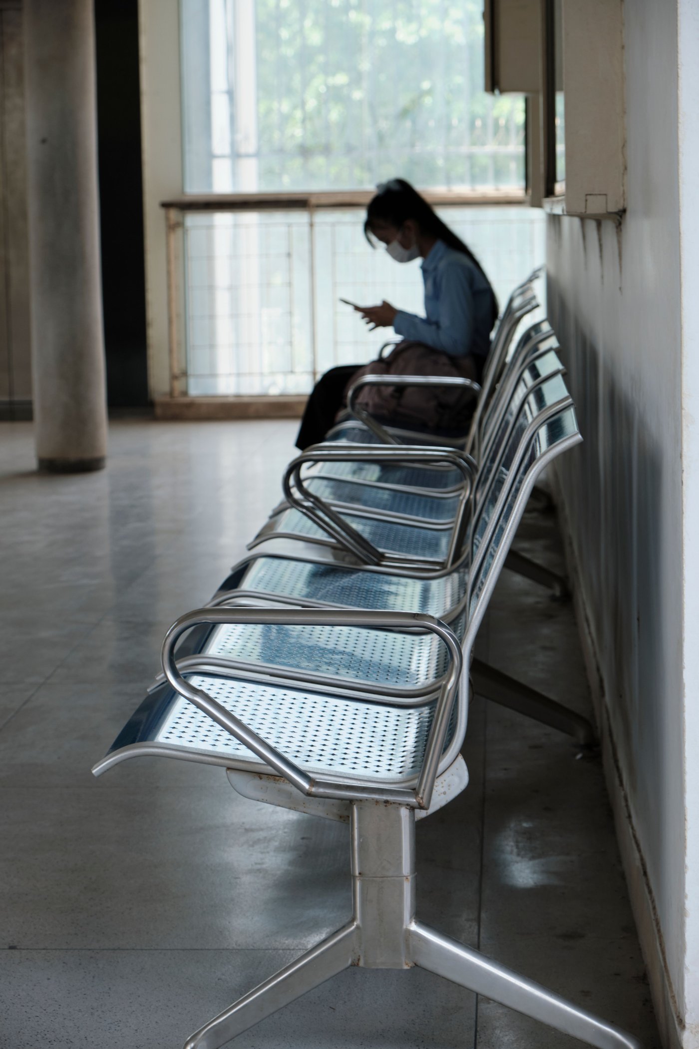 Persona sentada en una sala de espera consultando su celular antes de la cita